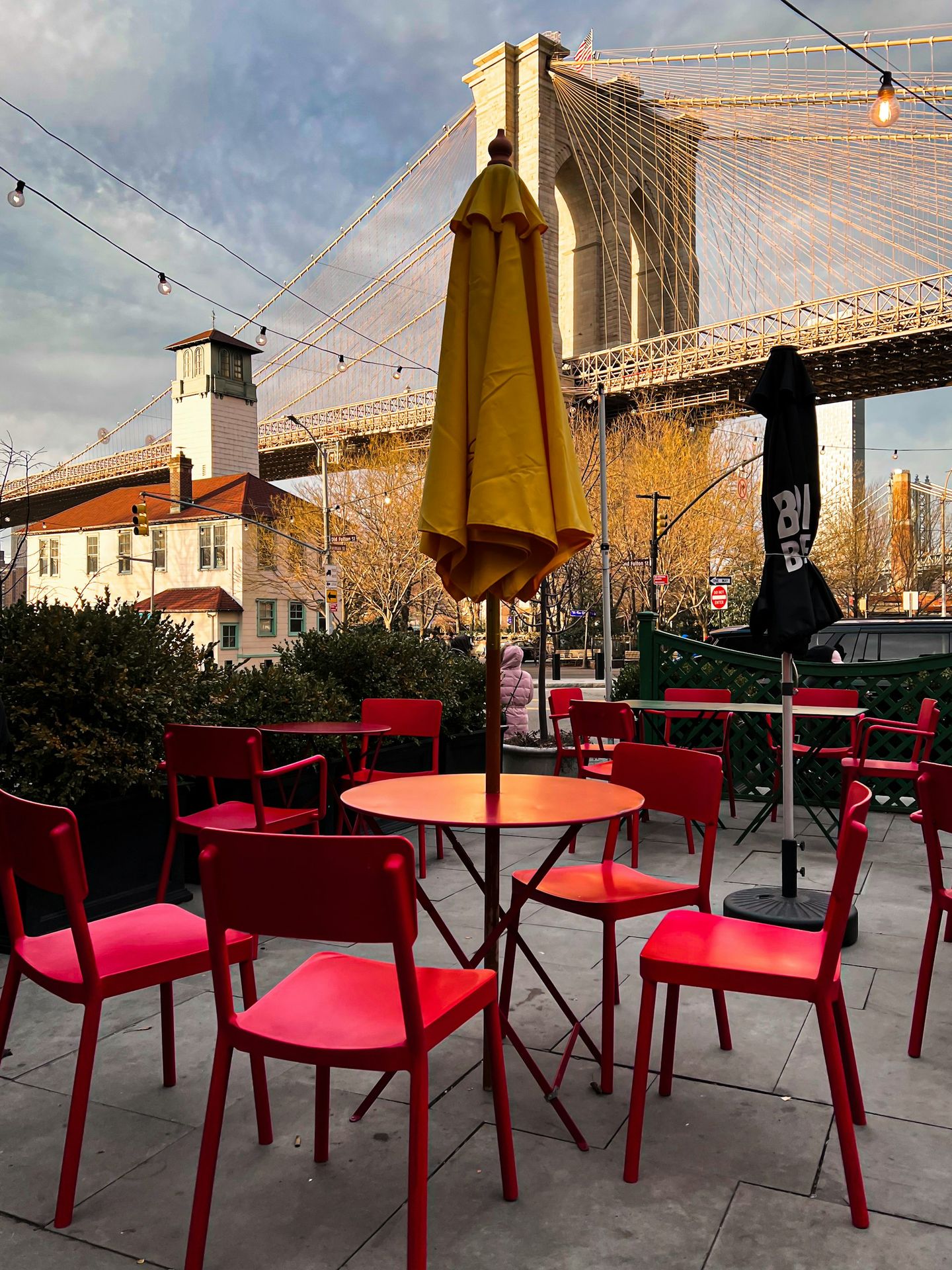 a table and chairs with an umbrella and a bridge in the background